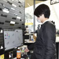 A shopper makes a purchase at an unmanned convenience store at Takanawa Gateway Station in Tokyo during a media preview last week. | ?¯