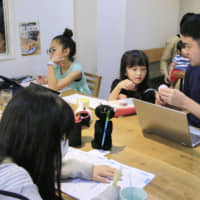 Parents work alongside their children at a cafe in Tokyo during an experimental telecommuting event last year. | KYODO