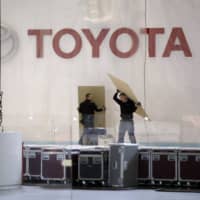 Workers dismantle a Toyota Motor Corp. pavilion at the canceled Geneva International Motor Show. Toyota said its idled manufacturing facilities in the U.S. will make face shields and masks. | BLOOMBERG