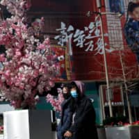 Women walk on a shopping street in Beijing on Tuesday. | REUTERS
