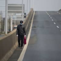 A man walks on an empty street in Wuhan, in China\'s central Hubei province, on Saturday. | AFP-JIJI