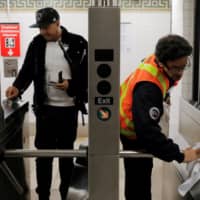 An MTA worker wipes down a turnstile at the Broad Street subway station after more cases of coronavirus were confirmed in New York City on Tuesday. | REUTERS