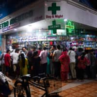 People gather at a pharmacy to buy supplies following the announcement of a government-imposed nationwide lockdown in Mumbai on Tuesday. | AFP-JIJI
