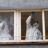 Sanitary workers clean a nursing home where a woman died and several residents and care providers have been diagnosed with coronavirus in Grado, Asturias, Spain, on Friday. | REUTERS