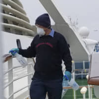 A cruise ship worker cleans a railing on the Grand Princess off the California coast on Thursday. | MICHELLE SMITH / VIA AP