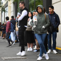 Hundreds of people line up outside a Centrelink government welfare center in Melbourne on March 23, when the forced closure of pubs, casinos, churches and gyms began across Australia. | AFP-JIJI