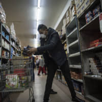 A man stocks up on groceries at a supermarket in Lenasia, Johannesburg, on Tuesday. | AP