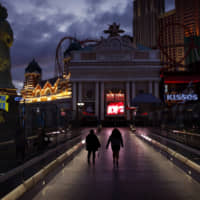 People walk Wednesday along the Las Vegas Strip, devoid of the usual crowds after casinos were ordered to shut down due to the coronavirus outbreak. | AP