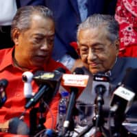 Mahathir Mohamad (right) listens to Muhyiddin Yassin during a news conference in April 2018, when both were allies. | REUTERS