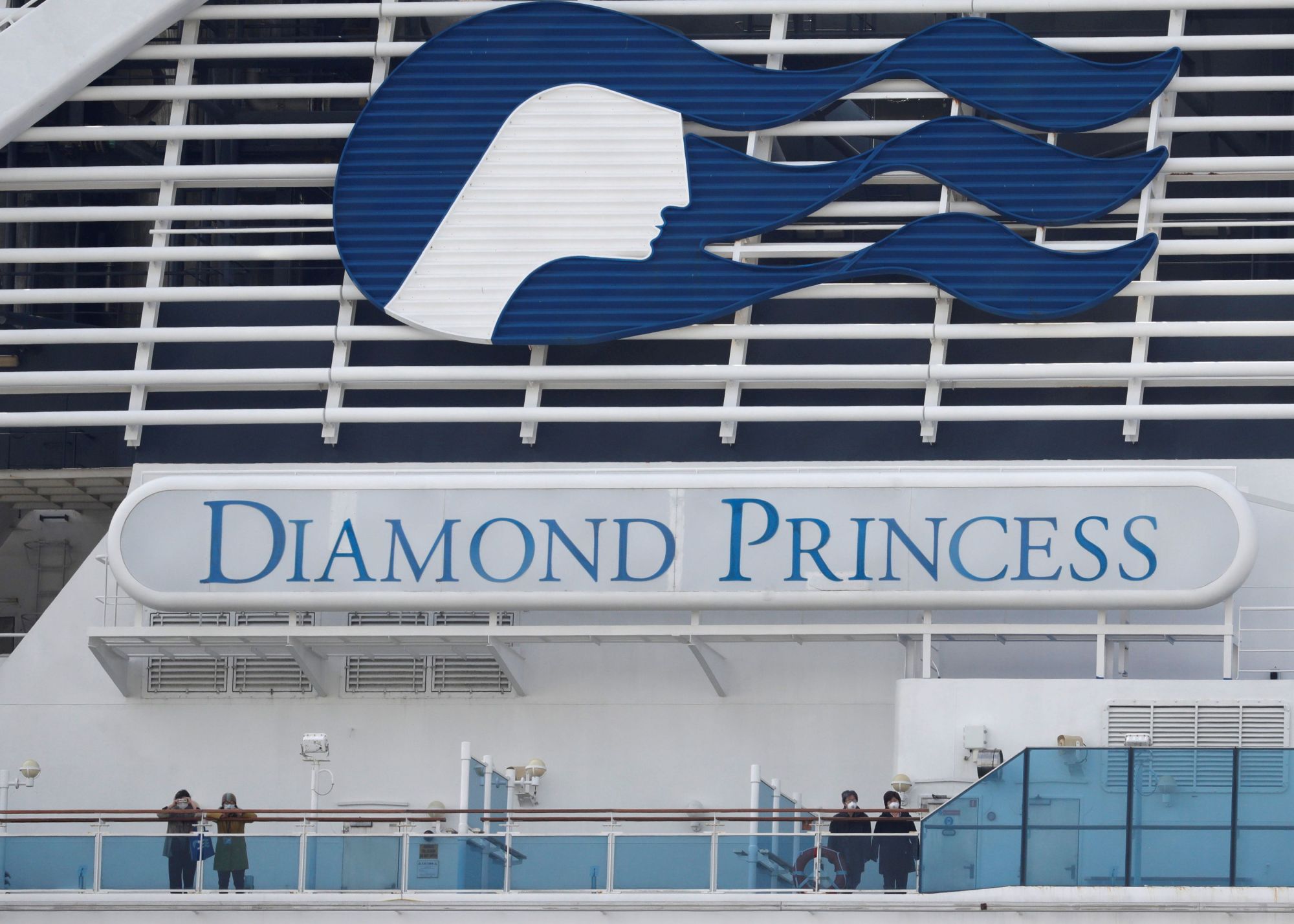 Masked passengers look on from aboard the coronavirus-hit Diamond Princess cruise ship docked at Yokohama on Feb. 20. | REUTERS