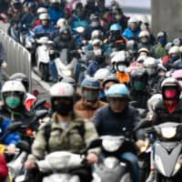 Motorcyclists wearing face masks to prevent the infections of the COVID-19 coronavirus, ride during the peak hours while heading to work in Taipei on Wednesday. Taiwan plans to bar all new arrivals by foreign nationals, adding to the growing ranks of governments shutting their borders in a bid to slow the global spread of the coronavirus. | AFP-JIJI