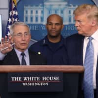 U.S. President Donald Trump listens as Director of the National Institute of Allergy and Infectious Diseases Anthony Fauci, a member of the coronavirus (COVID-19) task force, answers a question about the virus and the current outbreak during a news briefing at the White House on Monday. | REUTERS