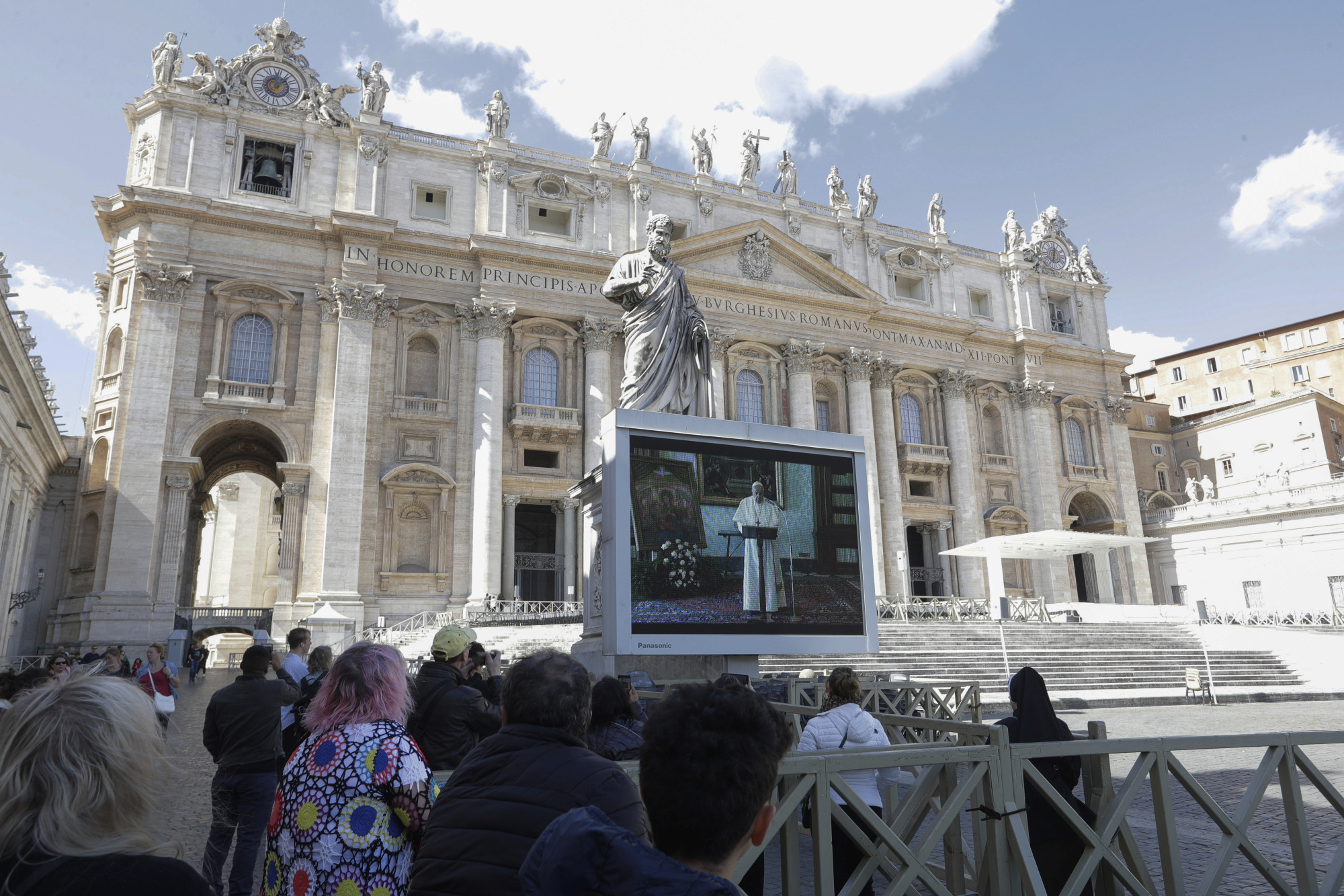Worshippers watch Pope Francis deliver the Angelus prayer on a giant screen to avoid crowds in St. Peter's Square at the Vatican on Sunday. | AP