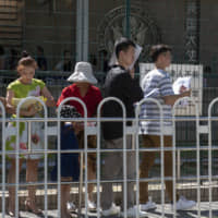 Visa applicants wait outside the U.S. Embassy in Beijing. | AP