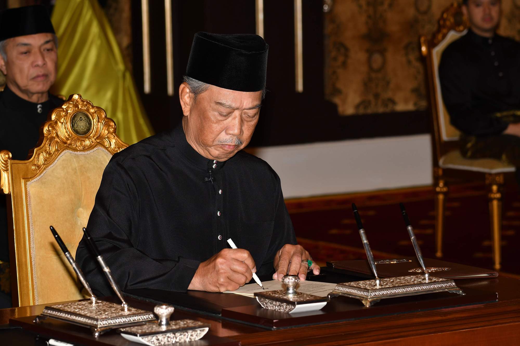 Malaysian Prime Minister Muhyiddin Yassin signs documents after taking the oath as the country's new leader at the National Palace in Kuala Lumpur on Sunday. | AFP-JIJI