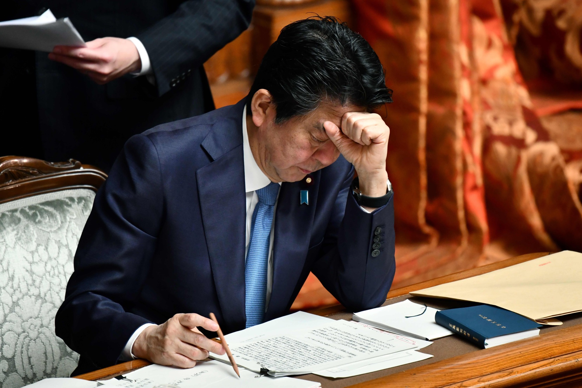 Prime Minister Shinzo Abe rests his head on his fist as he attends an Upper House plenary session at the Diet in Tokyo on Friday. | AFP-JIJI