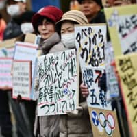 Protesters hold placards during a demonstration against nuclear energy, Prime Minister Shinzo Abe and the forthcoming Olympics Games, near the crippled Fukushima No. 1 nuclear power plant on Feb. 29, 2020. | AFP-JIJI