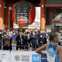 Spectators watch the Tokyo Marathon in front of Sensoji Temple in the Asakusa district on Sunday, with many wearing masks amid growing coronavirus infections. | KYODO