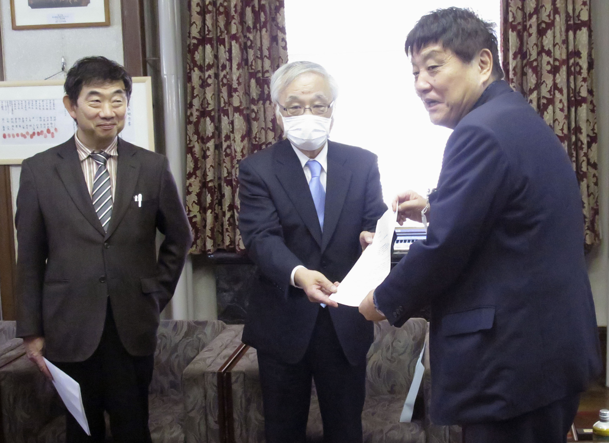 A medical worker hands a petition calling for enhanced medical capacity to Nagoya Mayor Takashi Kawamura (right) at Nagoya City Hall on Monday. | KYODO