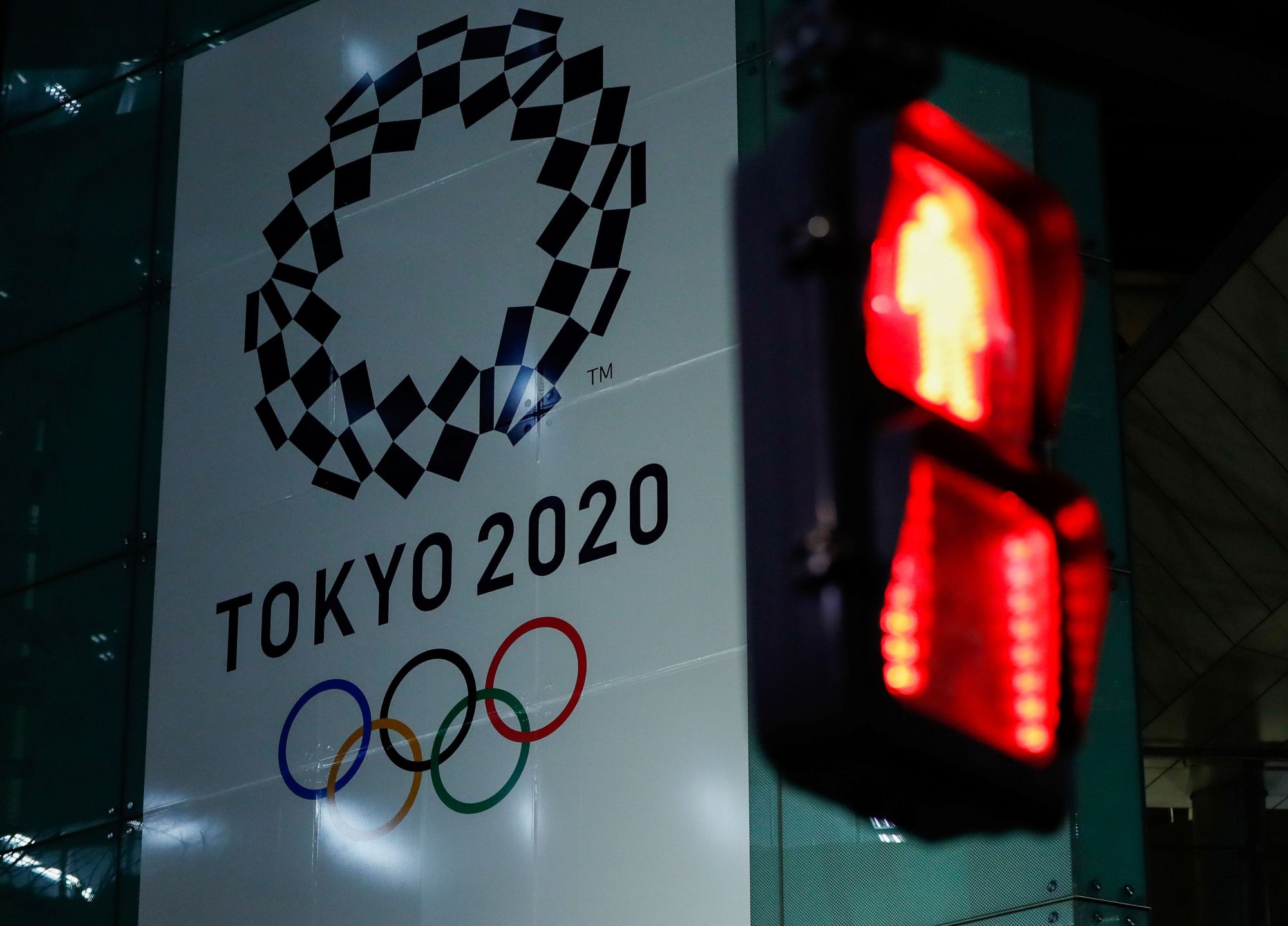 A banner for the upcoming Tokyo 2020 Olympics is seen through a traffic signal in the Japanese capital on Wednesday night. | REUTERS