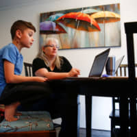 Chrissy Brackett (right) and her grandson Caidence Miller, a fourth grader at Cottage Lake Elementary in Woodinville, Washington state, struggle to navigate the school district\'s online learning system on March 11. | REUTERS