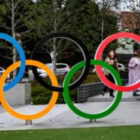 People take pictures of the Olympic Rings outside the closed Japan Olympic Museum in Tokyo on Friday, three days after the historic decision to postpone the Summer Games. | AFP-JIJI