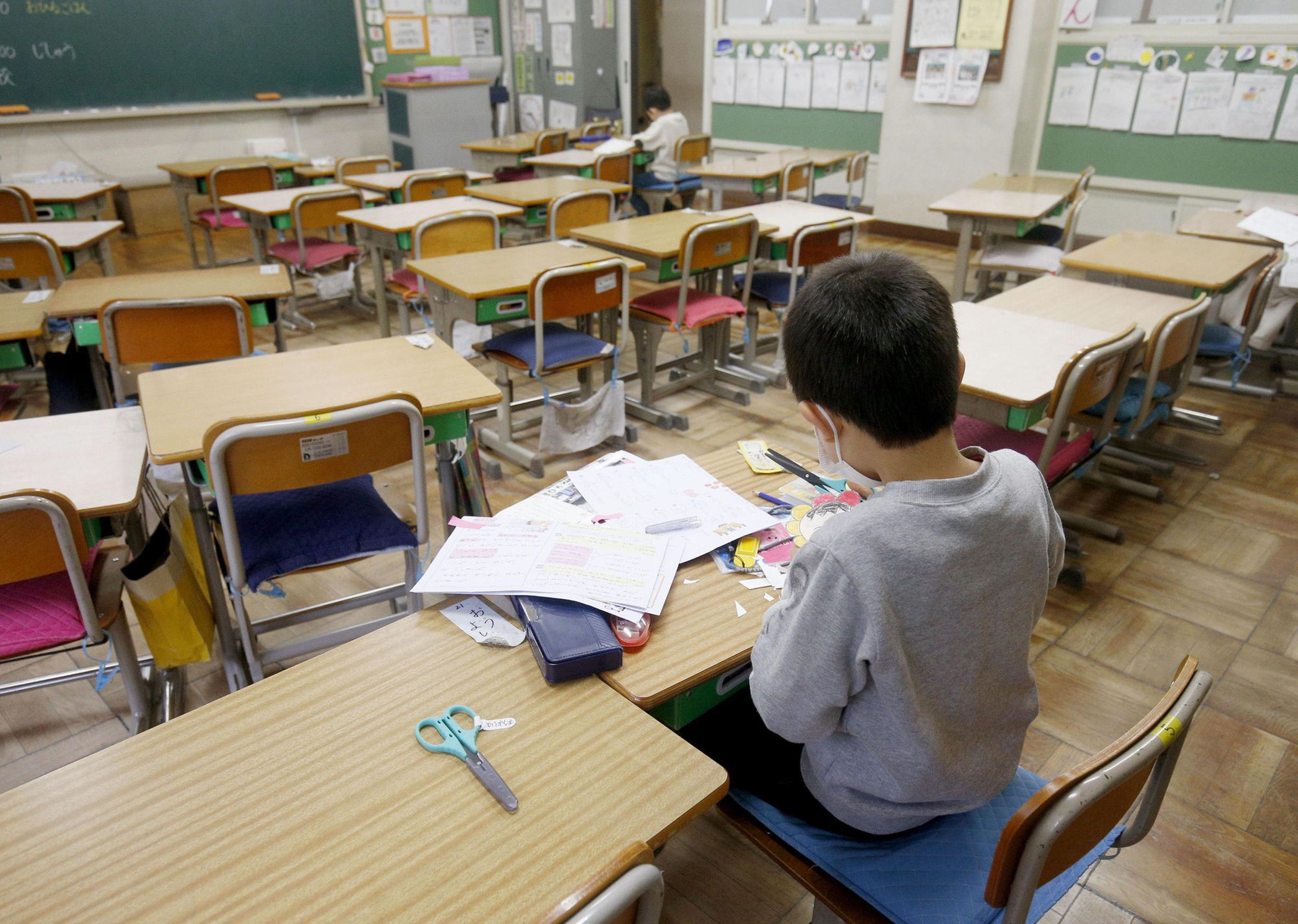 Two students study in an almost empty elementary school classroom in the city of Saitama on Monday. School closures began the same day, but some schools opened their doors for children whose parents were not at home. | KYODO
