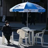 A woman sits alone in Tokyo\'s Ginza district on Sunday. | AFP-JIJI