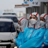 Medical staff work at a drive-thru testing center for the novel coronavirus at Yeungnam University Medical Center in Daegu, South Korea, on March 3. | REUTERS