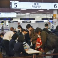 Travelers from international flights line up at a quarantine counter at Tokyo\'s Haneda Airport on Wednesday. | KYODO