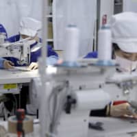 Employees sew disposable protective masks at a factory in Toyohashi, Aichi Prefecture, in January. | BLOOMBERG