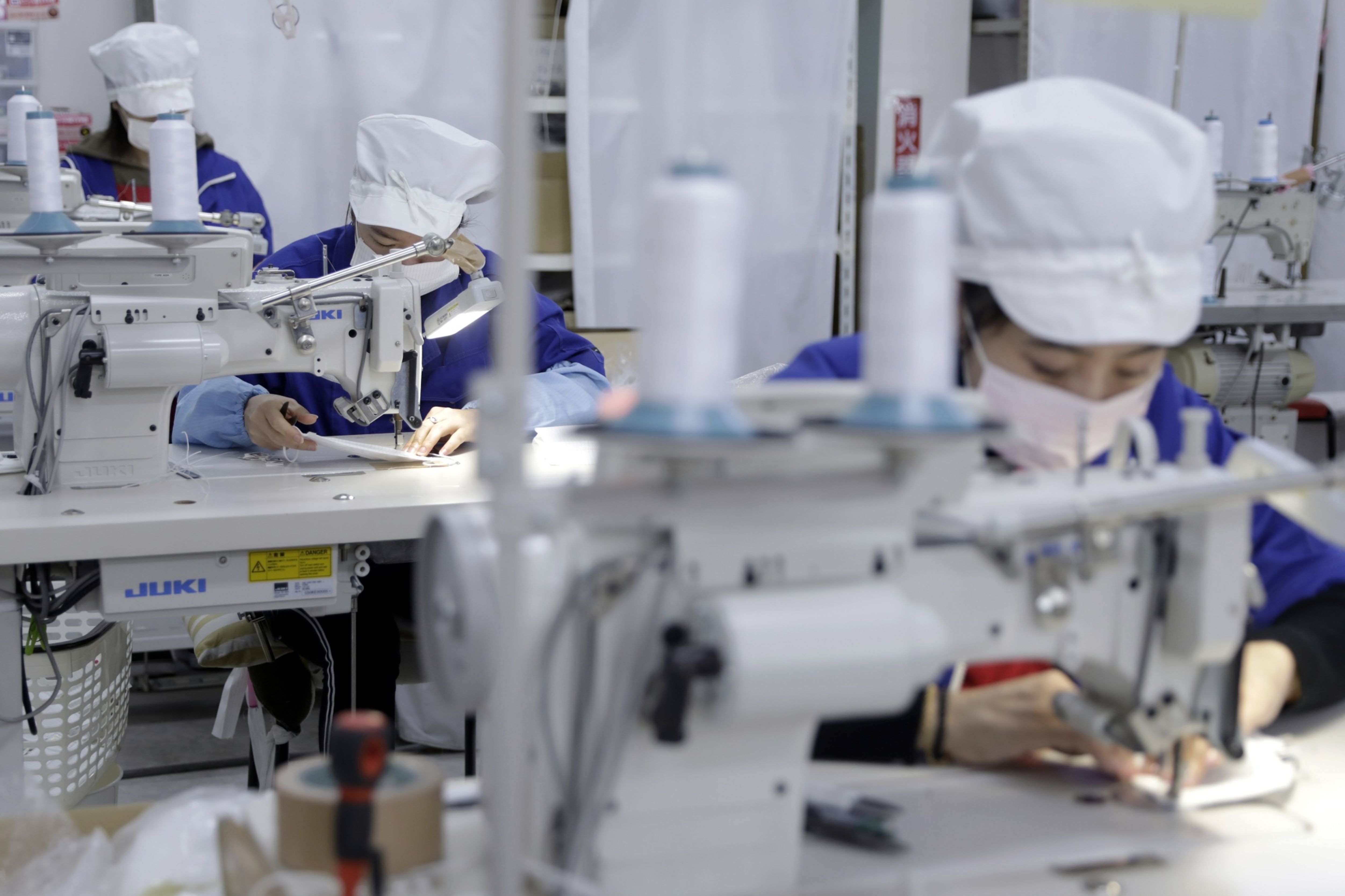 Employees sew disposable protective masks at a factory in Toyohashi, Aichi Prefecture, in January. | BLOOMBERG