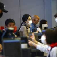 Passengers wearing protective masks check in at Kansai International Airport in Osaka. In just a matter of weeks, people in affected areas have become accustomed to wearing masks, stocking up on essentials, canceling social and business gatherings, scrapping travel plans and working from home.  | REUTERS