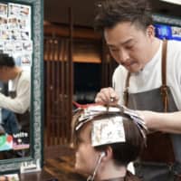 Koichi Nihei, a hairdresser at Pia Hair Salon Tokyo in Shibuya Ward, says he and his staff go without face masks, as the practice of wearing masks — less common overseas — could scare away its foreign patrons.  | RYUSEI TAKAHASHI