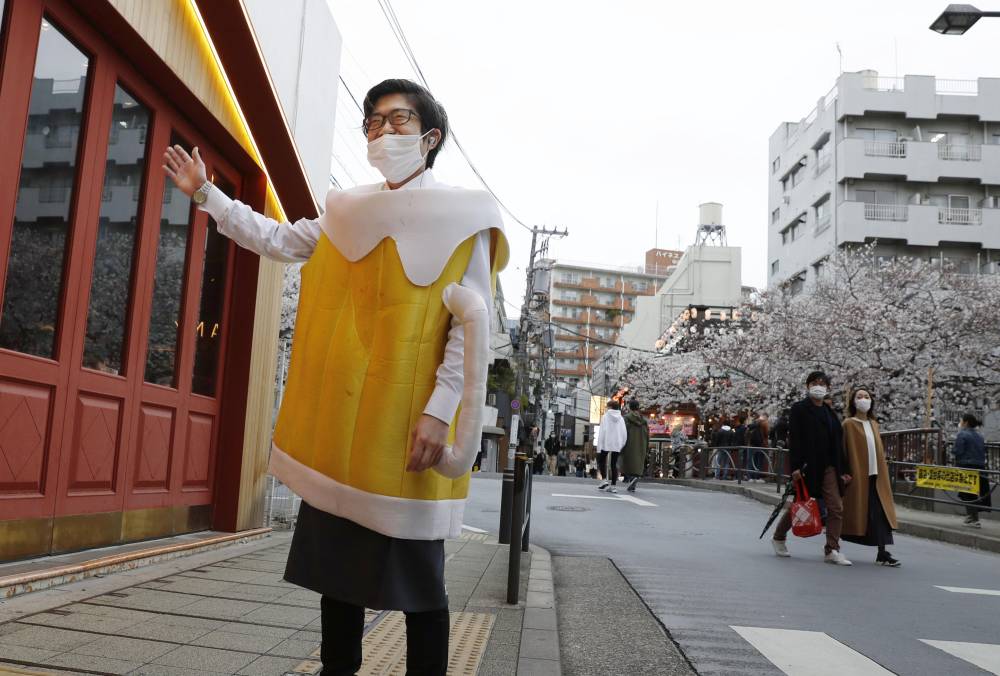 A restaurant employee dressed as a beer mug attempts to entice customers into an eatery in Tokyo's Meguro Ward on Saturday. | KYODO