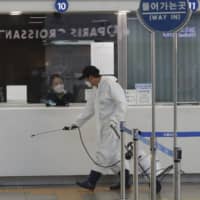 A worker sprays disinfectant as a precaution against the new coronavirus at the main railway station in Seoul on Sunday. | AP