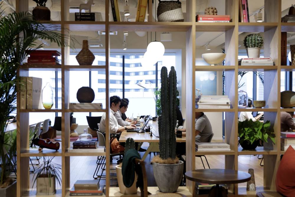Members sit at a communal worktable inside a WeWork shared office space in Yokohama in October.  | BLOOMBERG
