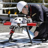 A postman checks a drone for mail delivery during a recent experiment in a Tokyo suburb. | KYODO