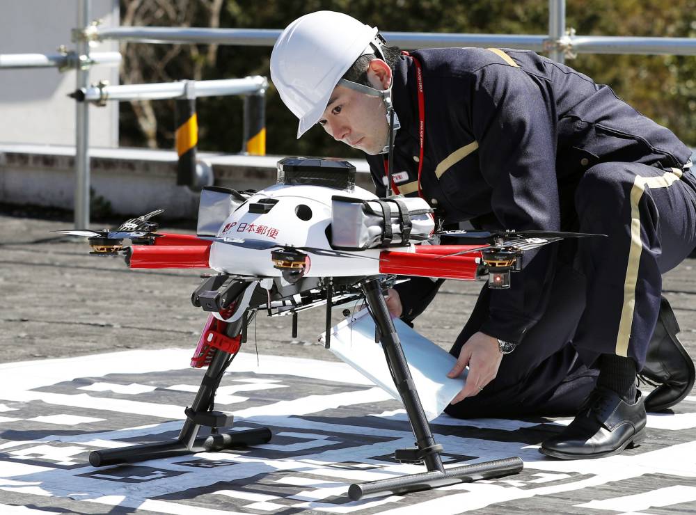 A postman checks a drone for mail delivery during a recent experiment in a Tokyo suburb. | KYODO