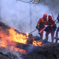 Firefighters on Tuesday work on extinguishing a forest fire that started near Xichang in Liangshan prefecture of Sichuan province, China. | CHINA DAILY / VIA REUTERS  