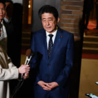 Prime Minister Shinzo Abe talks to journalists in front of his official residence Tuesday. He said the president of the International Olympic Committee agreed \"100 percent\" with postponing the Summer Olympics for about a year. | AP