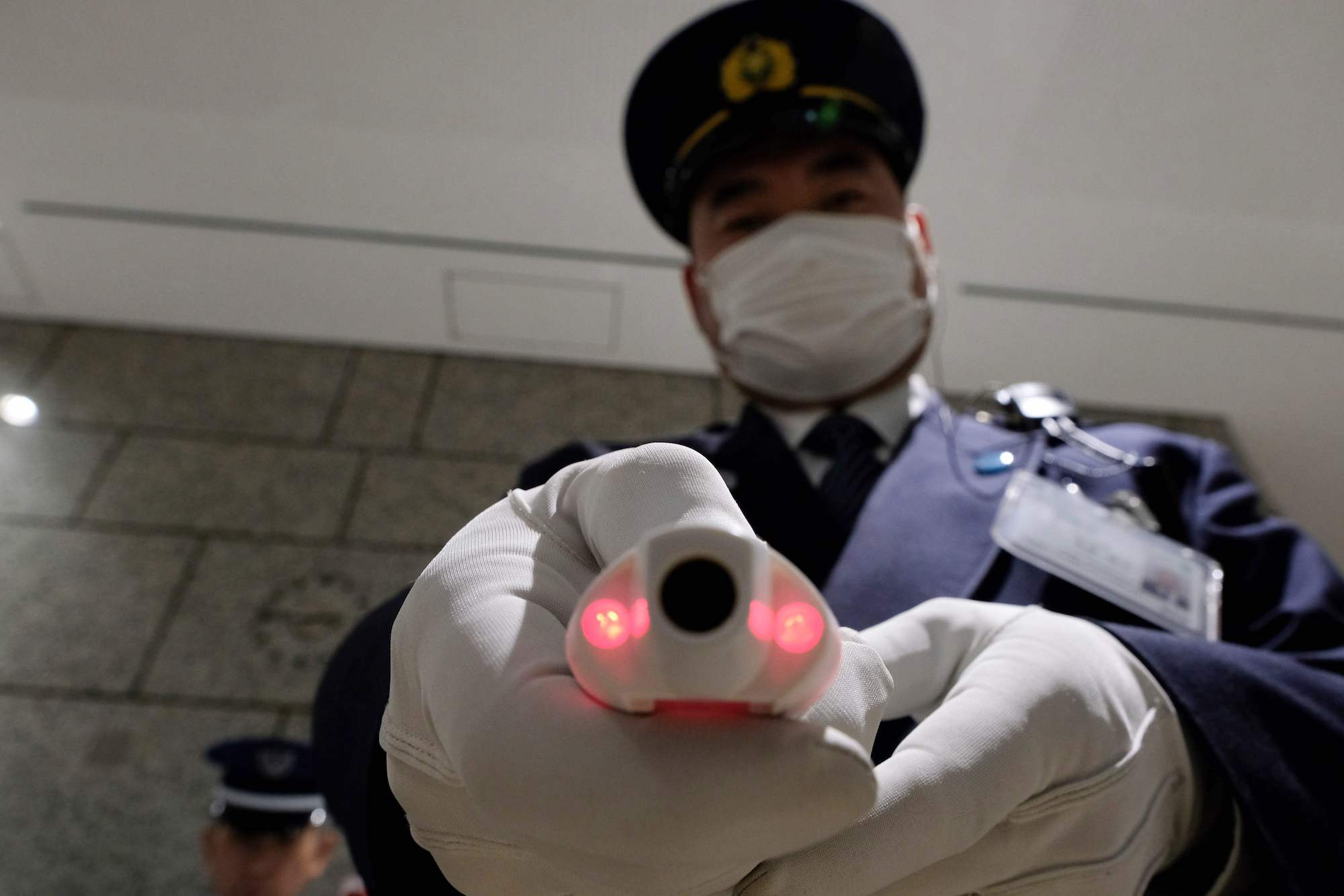 A security guard shows a body temperature-measuring device at the reception of the Tokyo Metropolitan Government office in Tokyo on Thursday. Japan will quarantine all passengers arriving from China and South Korea, the country's prime minister said on March 5. | AFP-JIJI