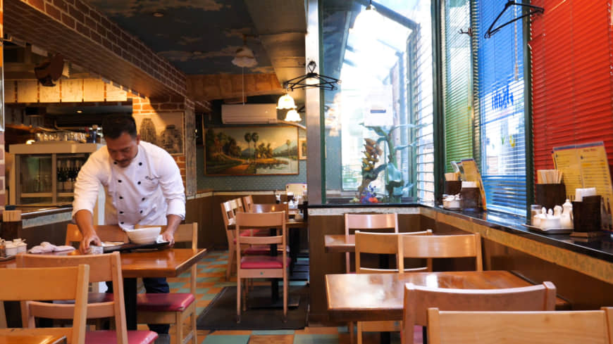 Culinary inheritance: Second-generation owner Shuji Go tidies the main dining room at Angkor Wat, which his father opened in 1982. | CHISATO TANAKA