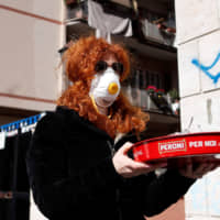 A woman  carries a tray in Rome on March 11, the second day of an unprecedented lockdown across the nation imposed to slow the outbreak of COVID-19. | REUTERS