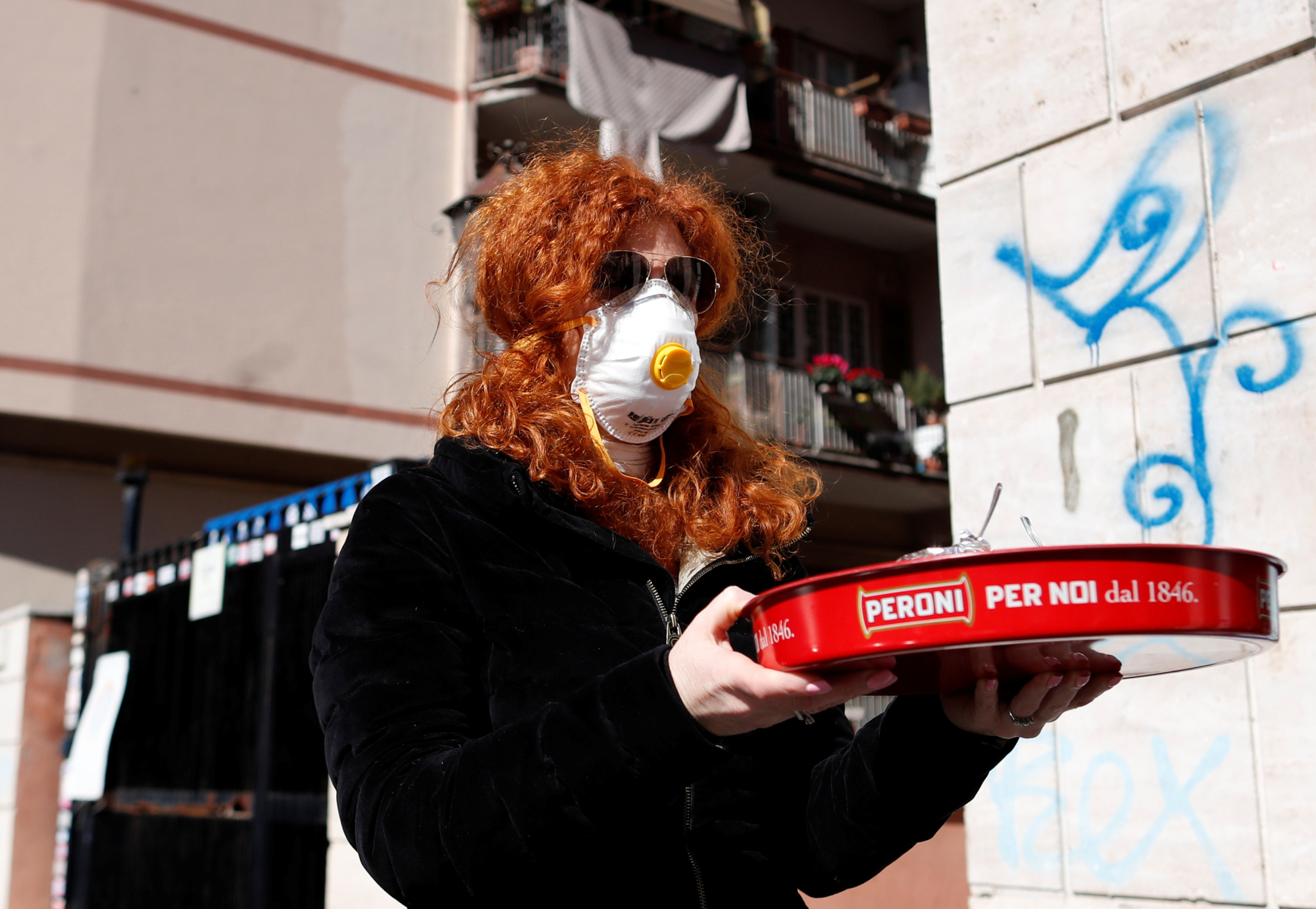 A woman  carries a tray in Rome on March 11, the second day of an unprecedented lockdown across the nation imposed to slow the outbreak of COVID-19. | REUTERS