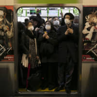 Commuters wearing masks stand in a packed train at Shinagawa Station on March 2. | AP