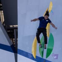 A Tokyo 2020 organizing staff member jumps after climbing a wall during a bouldering test on Friday at Aomi Urban Sports Park. | AFP-JIJI