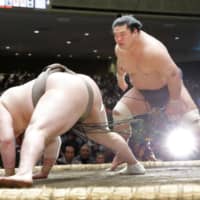 Myogiryu (right) defeats yokozuna Hakuho on the third day of the New Year Grand Sumo Tournament at Ryogoku Kokugikan on Jan. 14. | KYODO