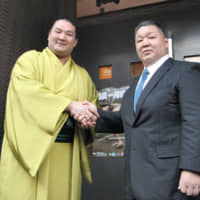 Former makuuchi wrestler Akinoshima (right), now known as Takadagawa stablemaster, shakes hands with Ryuden on Dec. 26, 2017, in Koto Ward. | KYODO