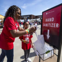 Fans pull sanitizing wipes from a dispenser outside Toyota Stadium before a SheBelieves Cup match between England and Spain on March 11 in Frisco, Texas. | AP